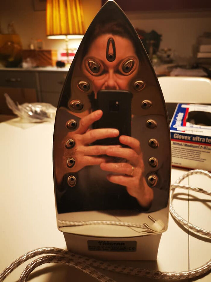 Distorted reflection on an iron's surface creating a funny and unusual face in a mirror reflection photo.