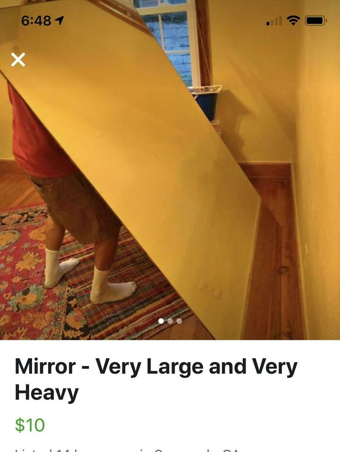 Person struggling to carry a very large and heavy mirror, highlighting humorous mirror reflection selling moments.