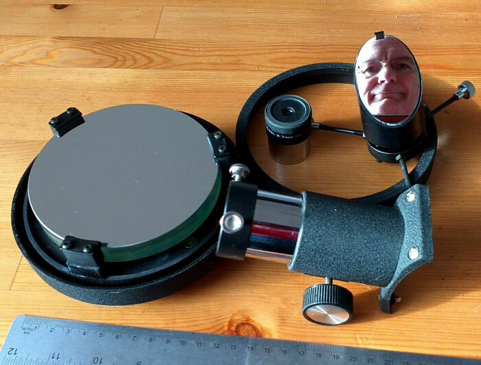 Optical device with mirror reflecting a man's face, illustrating humorous mirror reflection selling moments.