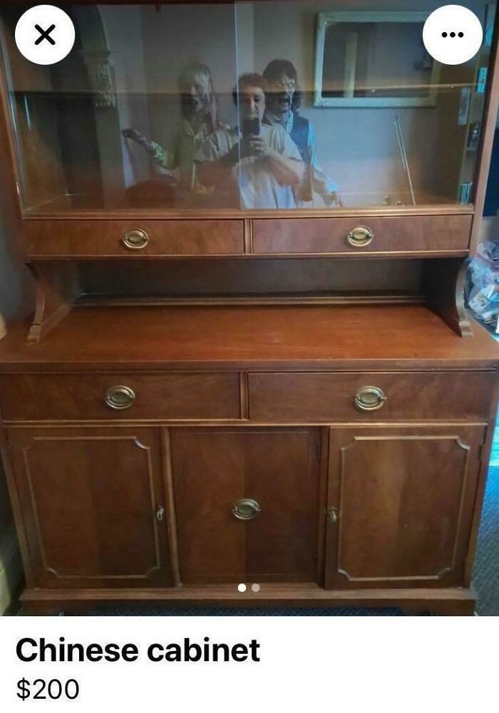 Wooden Chinese cabinet for sale with a mirror reflecting three people taking a photo, showcasing a funny mirror reflection moment.
