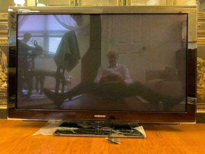 Reflection of a person sitting with legs spread, captured on a large Samsung TV screen acting like a mirror.