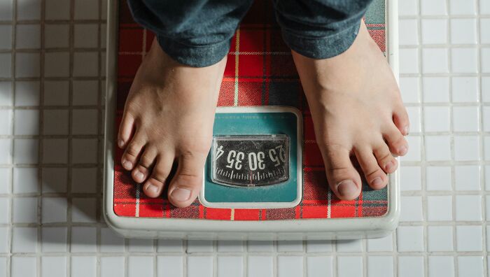 Person standing barefoot on a red plaid scale in a tiled bathroom, symbolizing chaotic and dramatic breakup stories.