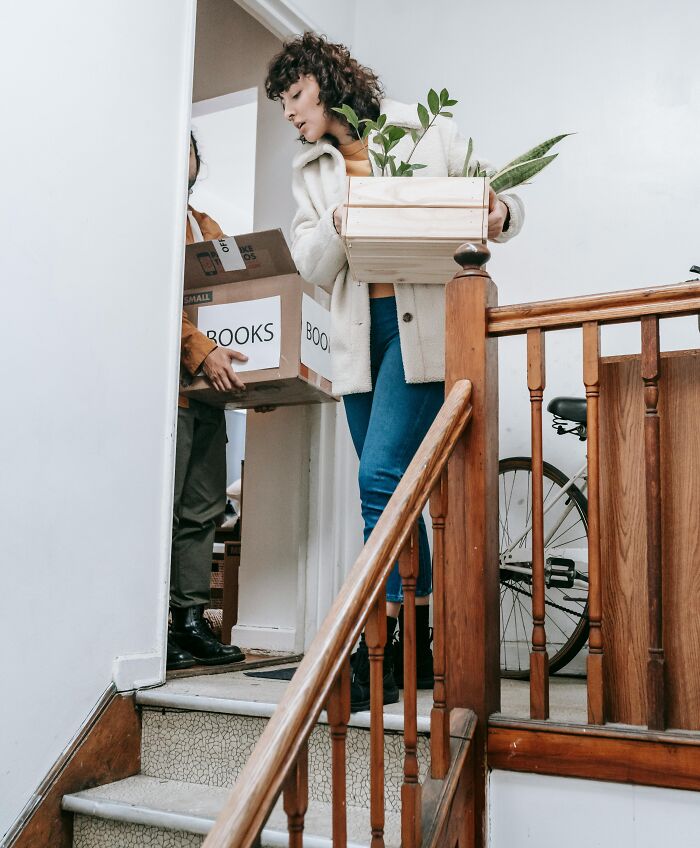 Two people carrying boxes while moving out, illustrating chaotic and dramatic breakup stories at home.