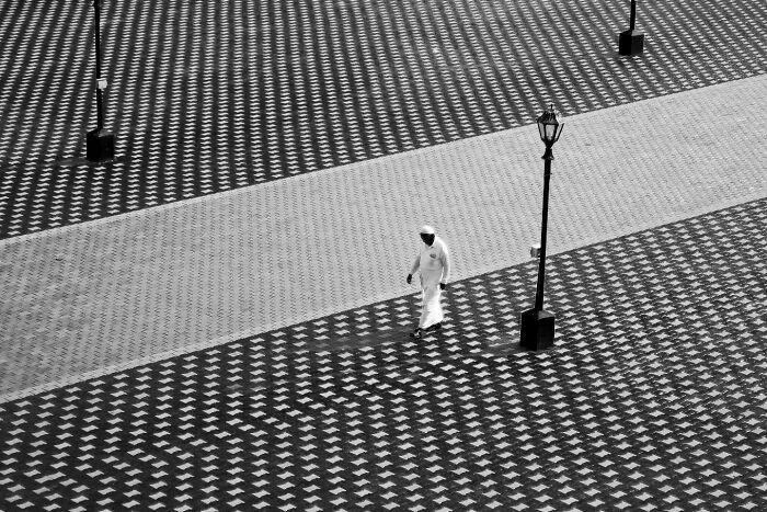 Black and white street photograph capturing the beauty of everyday life in India with geometric patterned pavement and a lone pedestrian.