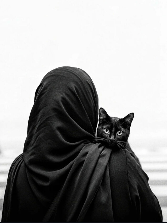 Woman in black covering with a black cat on her shoulder, capturing the beauty of everyday life in India street photography.