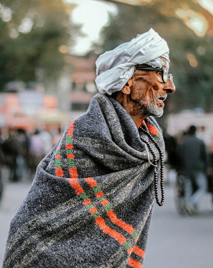 Elderly man wrapped in a patterned shawl wearing a white turban and glasses, capturing everyday life in India by street photographer