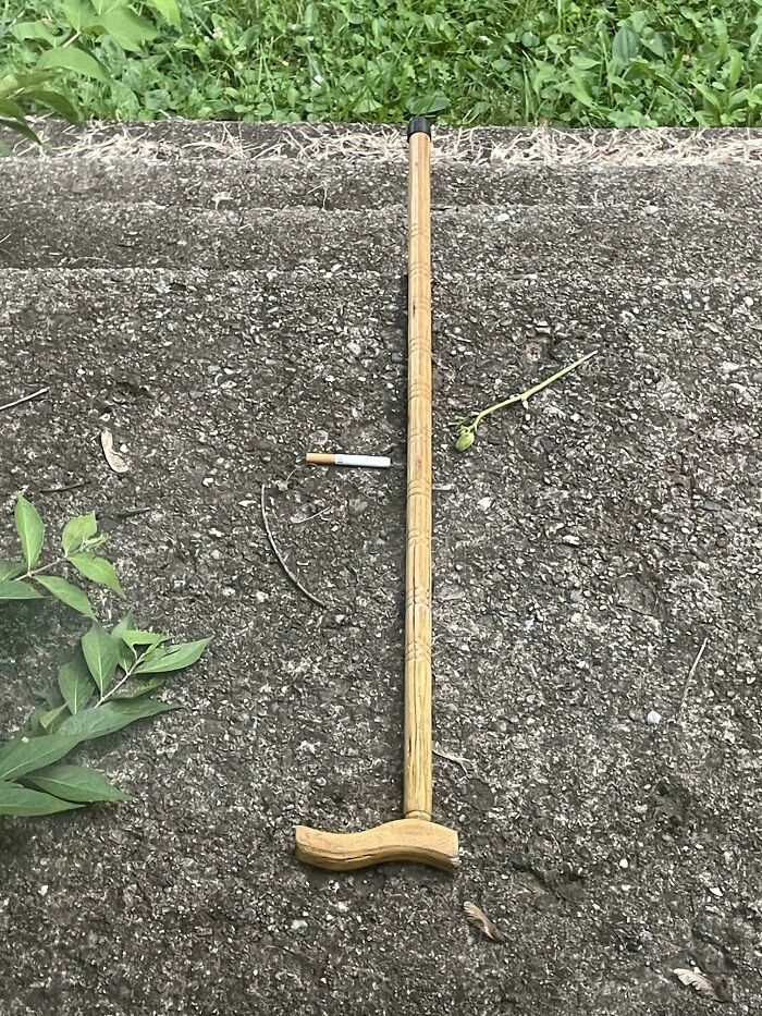 Wooden cane and cigarette lying on asphalt with grass nearby, one of the interesting group of unexplained things.