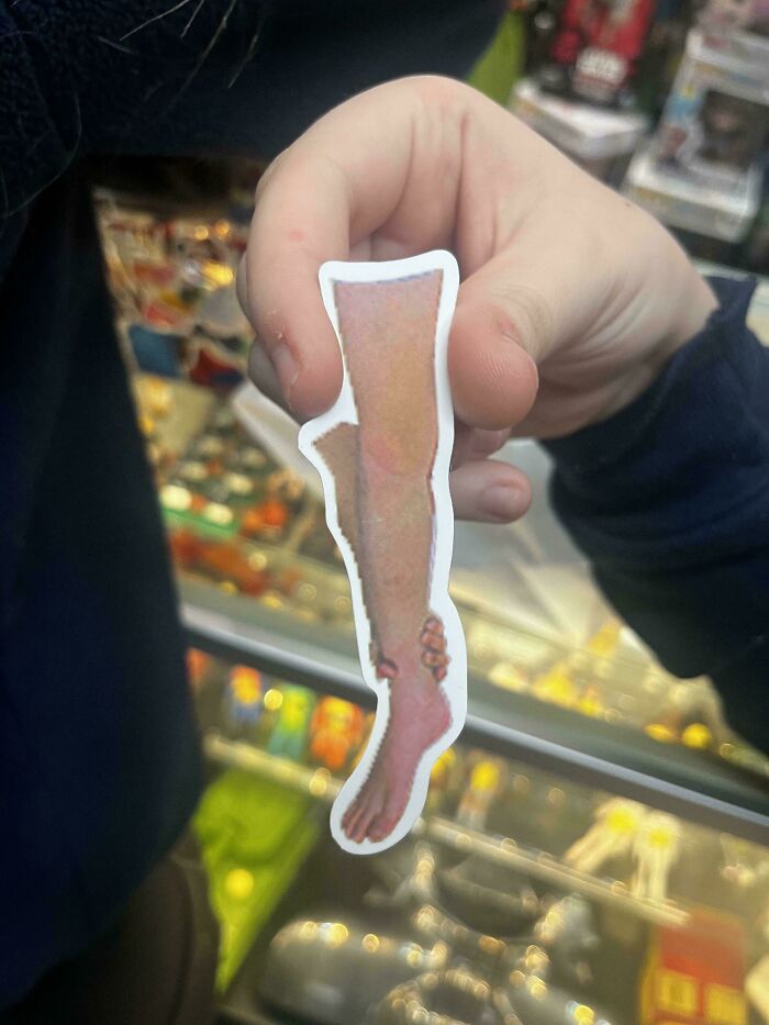 Hand holding a sticker showing a distorted leg and foot, illustrating some things that cannot be explained from this interesting group.