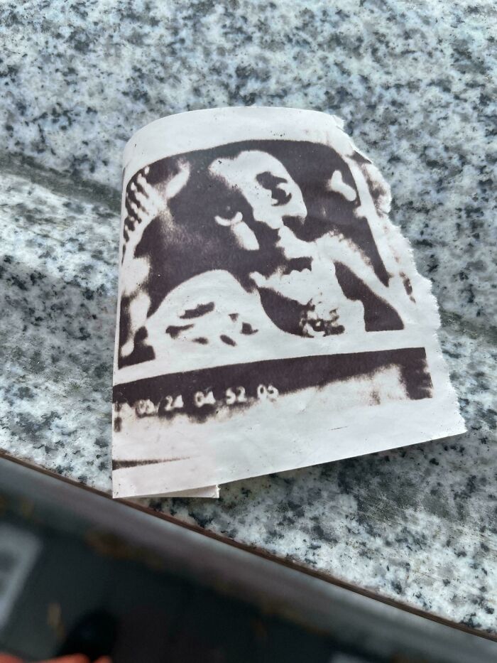 Faded black and white printout of a mysterious face fragment on rough granite surface showcasing unexplained group content.
