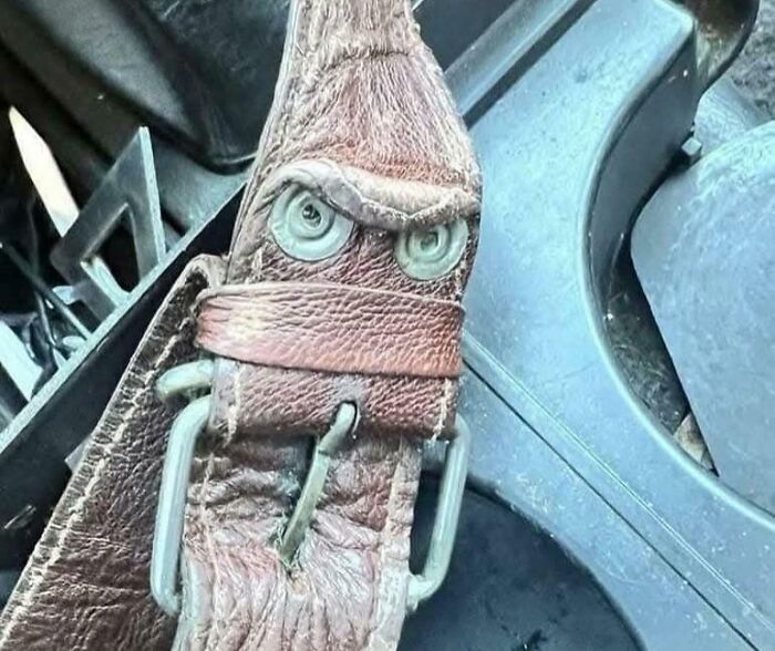 Close-up of an old leather belt buckle resembling an angry face, perfect for Harry Potter memes about Gryffindor common room moments.