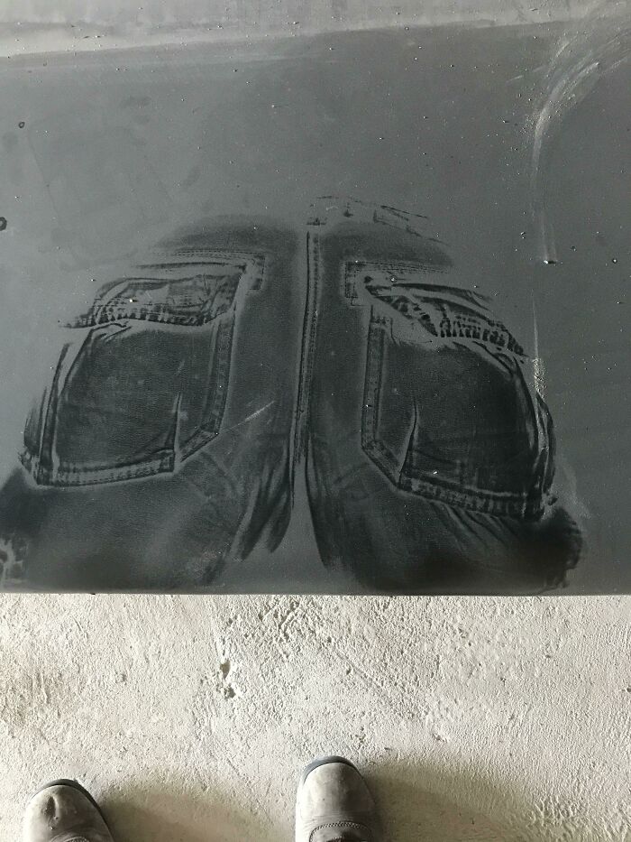 Dust outline of jeans pockets on a black surface with boots on a dusty floor in interesting pics collection