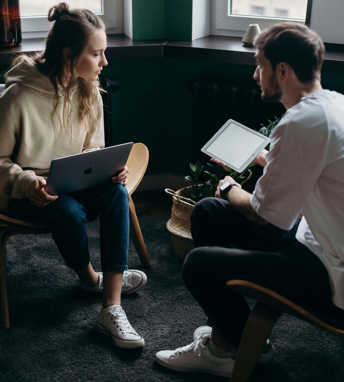 Young couple having a tense conversation with digital devices, illustrating chaotic and dramatic breakup stories.