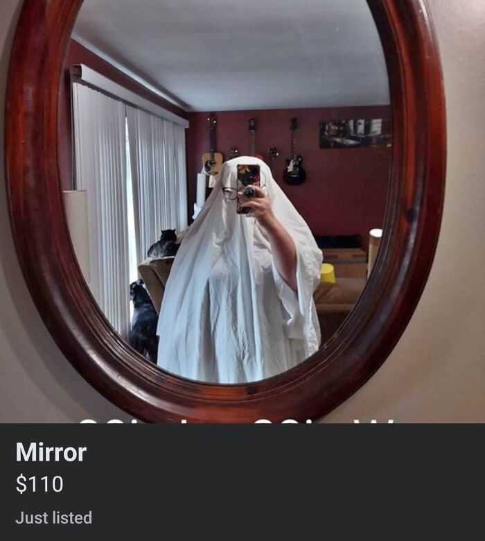 Person dressed as a ghost taking a selfie in a wooden-framed mirror, highlighting funny mirror reflection selling moments.