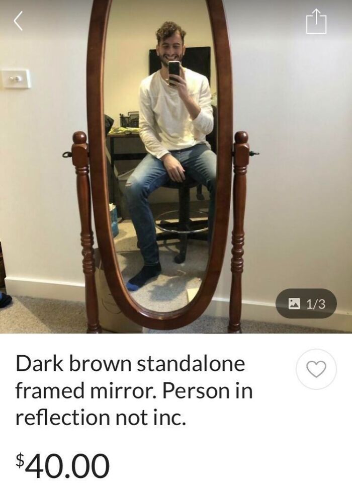 Dark brown standalone framed mirror for sale, with a person reflected sitting on a chair wearing casual clothes.