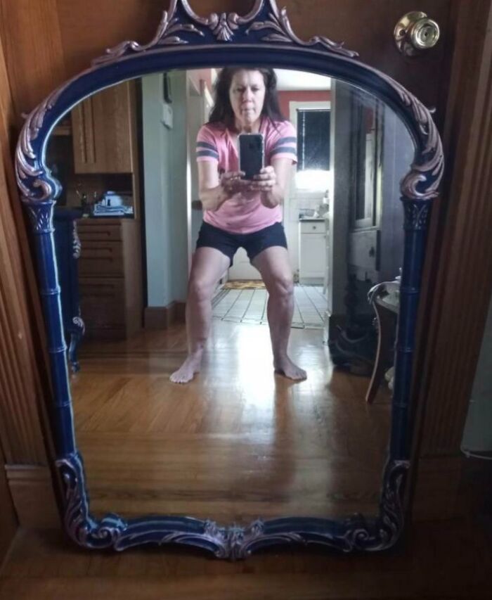 Woman taking a photo in an ornate mirror, showing a reflection that humorously highlights the mirror's unique selling point.