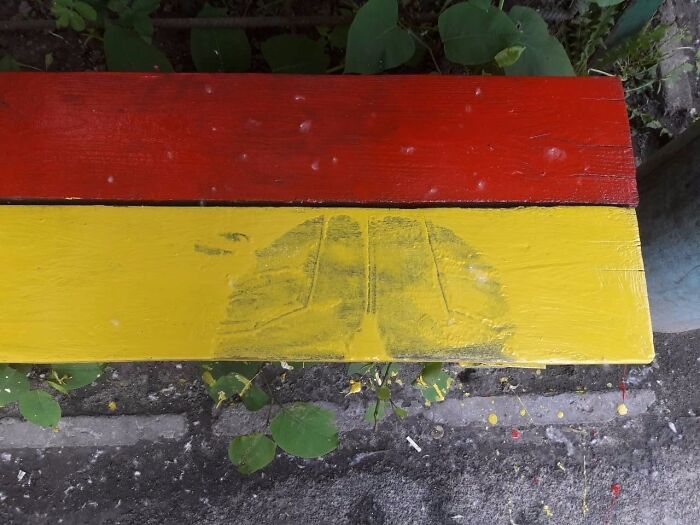 Worn and messy bench painted in red and yellow, showing signs that today feels like a total mess outdoors.