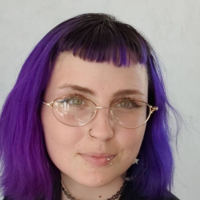 Person with short, uneven purple hair and glasses, showcasing a hilariously tragic hair accident style.