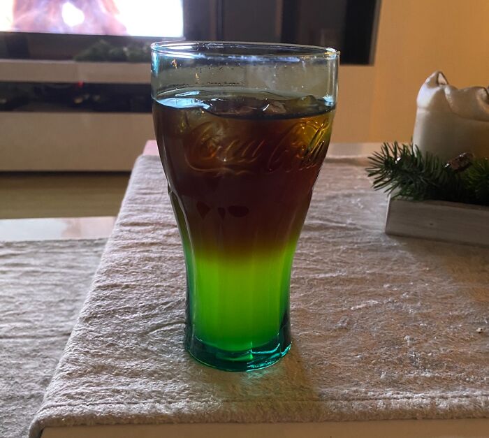 Layered green and brown drink in a Coca-Cola glass, showcasing one of the interesting pics that answer unexpected questions.
