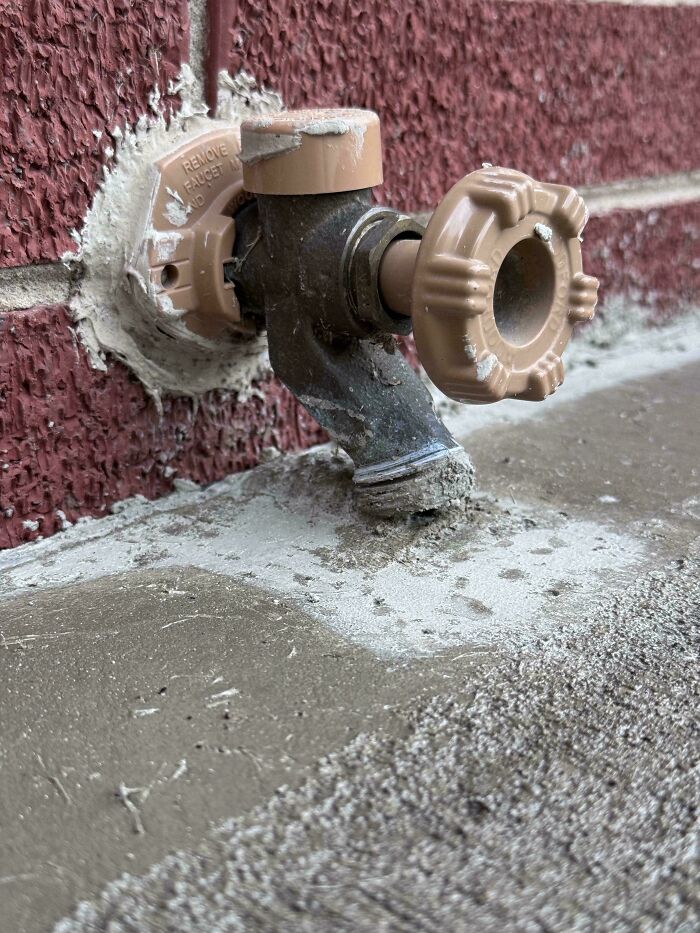 Outdoor faucet with c*****d and uneven concrete base, showing a messy and deteriorated condition in a close-up view.