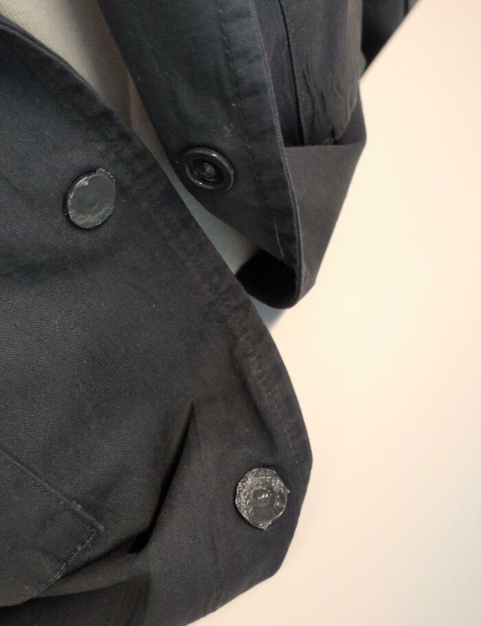 Close-up of a black jacket with damaged buttons, illustrating a total mess and things that can always get worse.
