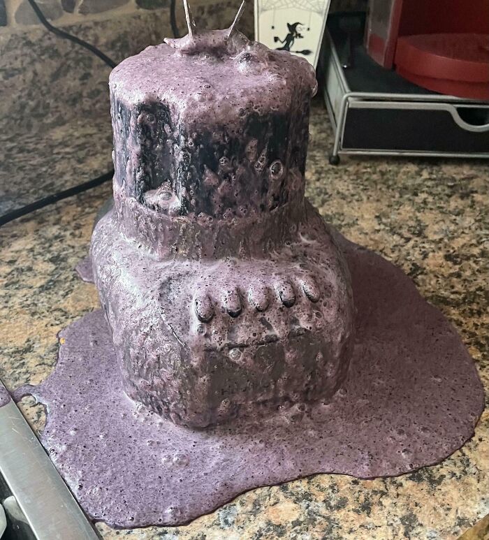 Kitchen blender overflowing with purple smoothie mess on granite countertop, showing a total mess kitchen disaster.