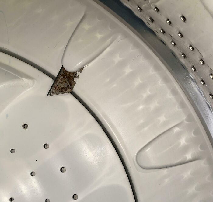 Washing machine drum with broken and rusty internal plastic part, showing a total mess inside the appliance.
