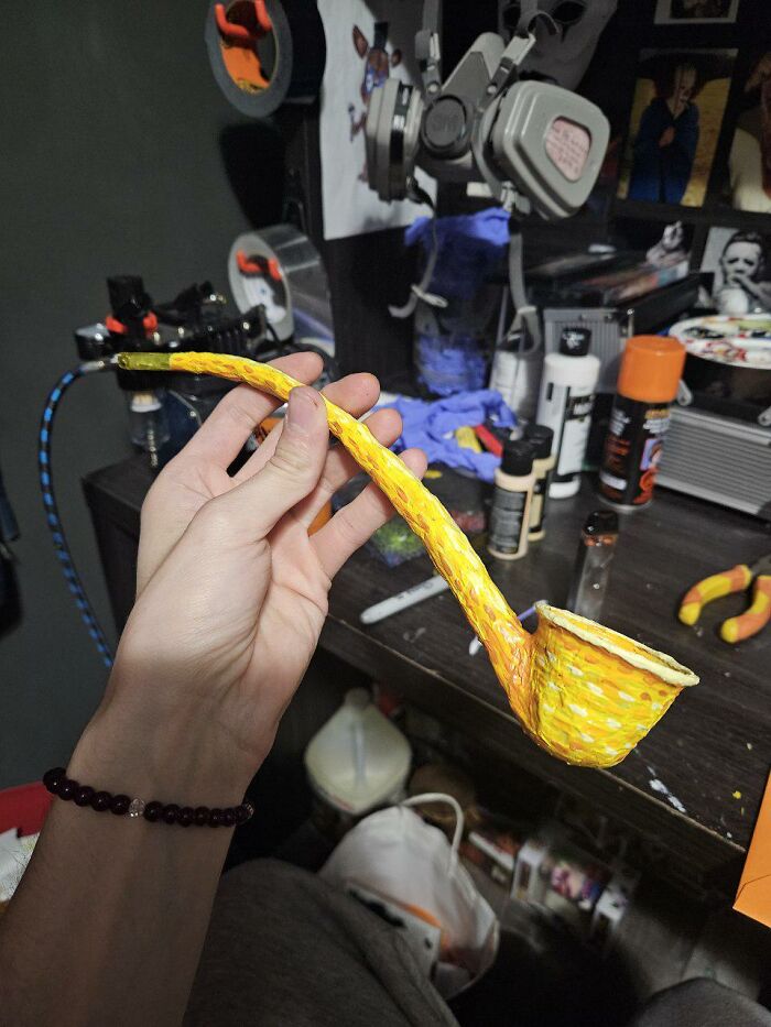 Hand-painted yellow pipe held by artist preparing Vincent van Gogh Halloween makeup and costume in workspace.