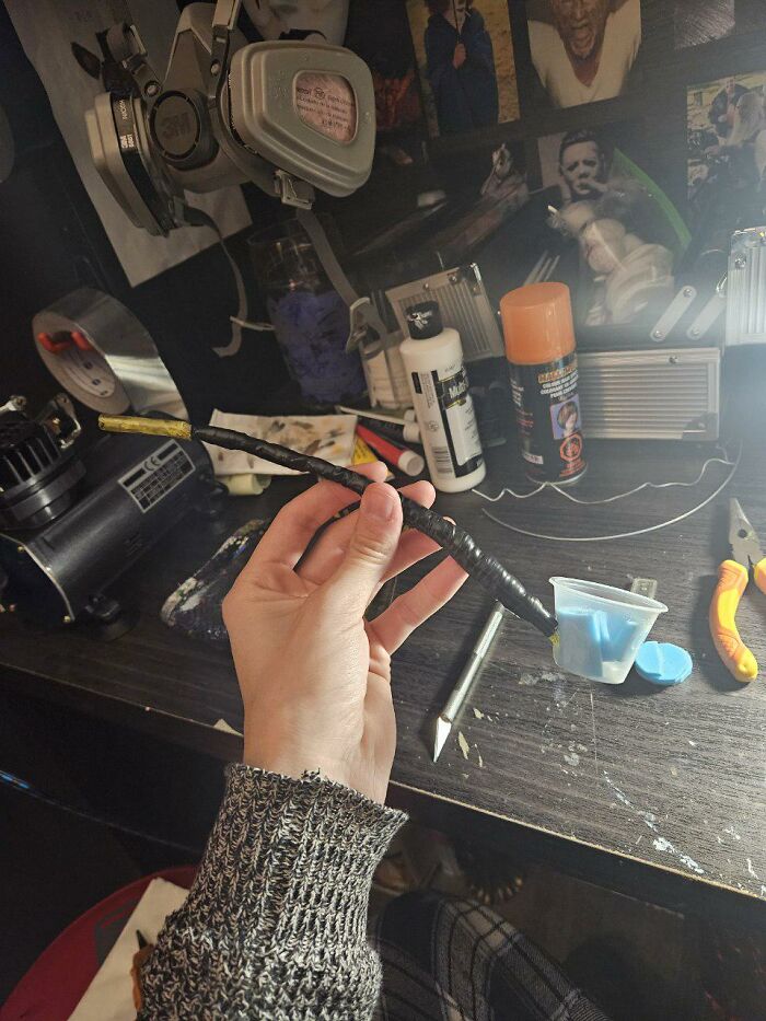 Artist holding a hand-painted makeup tool for Vincent van Gogh costume in a creative workspace with supplies.
