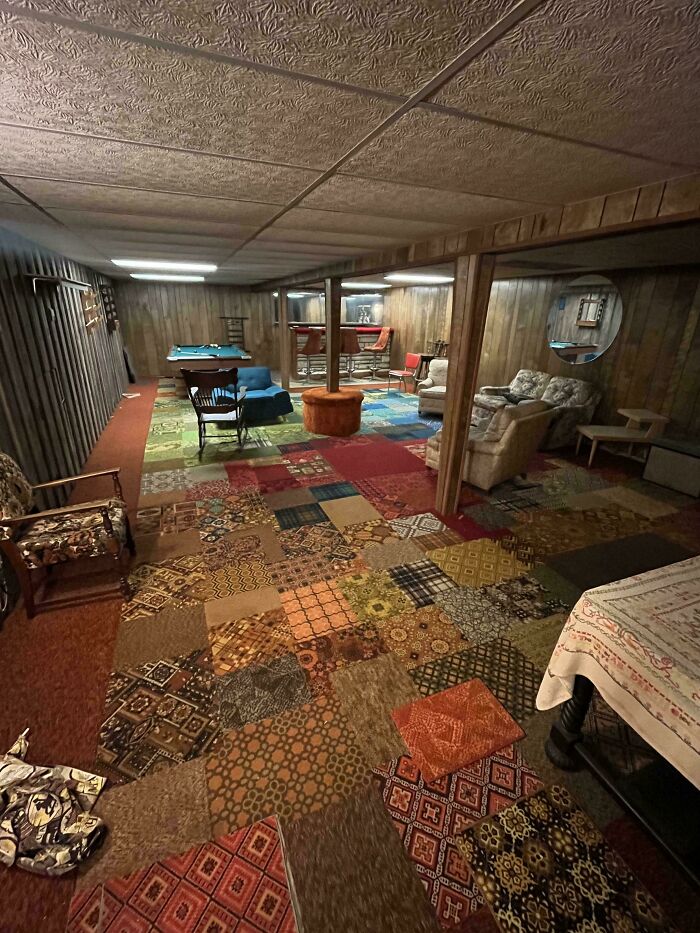 Retro basement recreation room in a charming old home featuring vintage furniture and a patchwork carpet design.