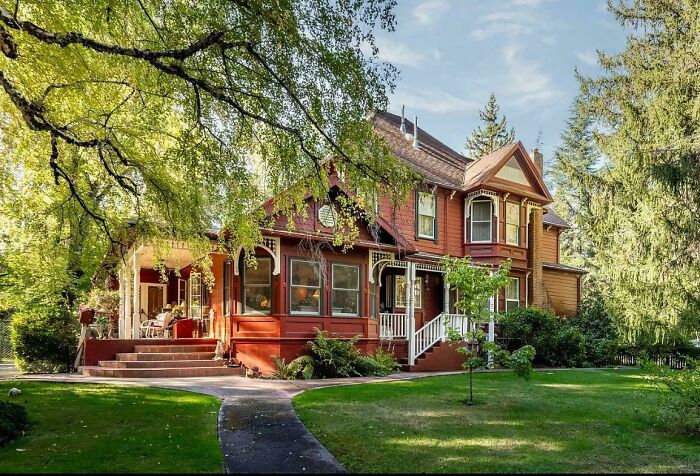 Charming old home with detailed architecture surrounded by lush greenery capturing timeless storybook appeal.