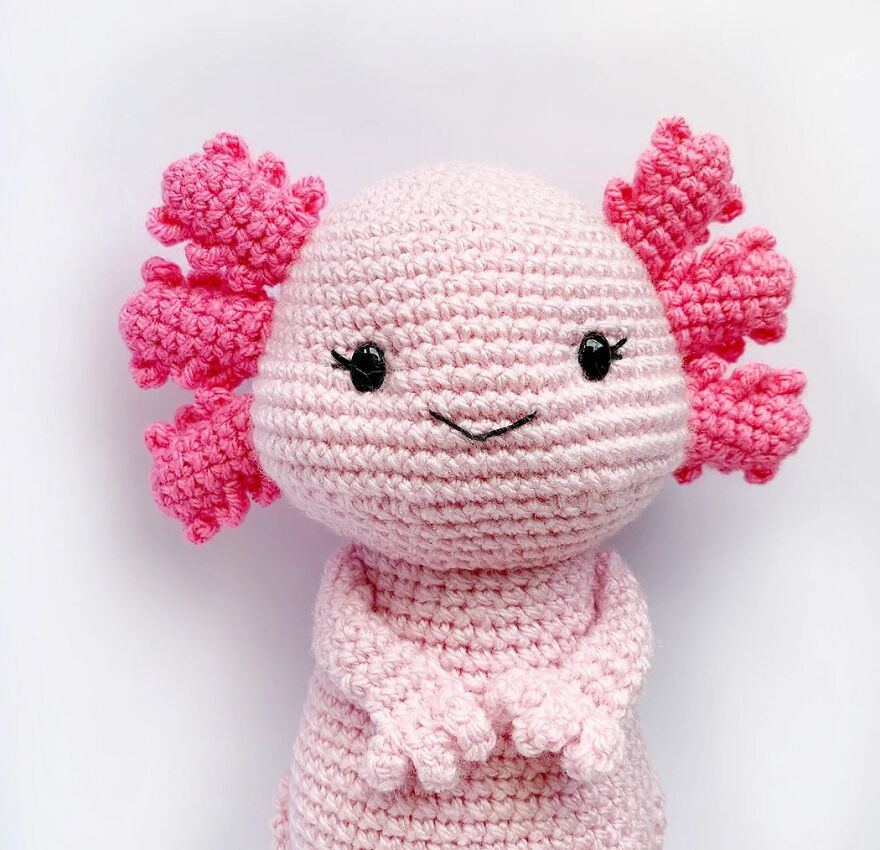 Crochet animal of an axolotl with pink details and a smiling face, showcasing handmade charm and personality.