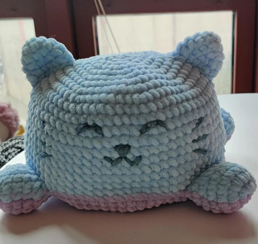 Soft blue crochet animal with stitched closed eyes and whiskers, showcasing personality in a handmade crochet toy design.