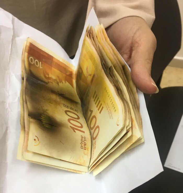 Burnt 100 shekel bills held in a hand inside an envelope, showing interesting pics that answer curious questions.