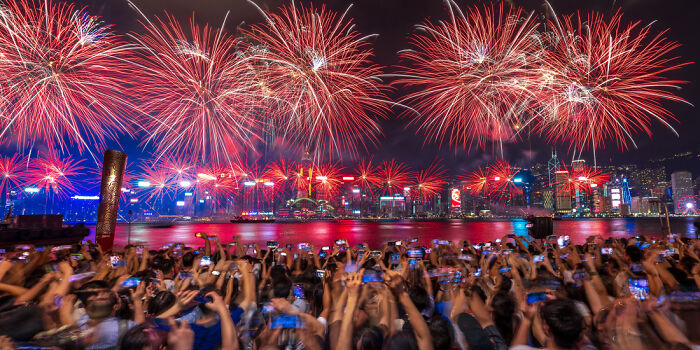 Crowd capturing vibrant panoramic fireworks display over city skyline at night, showcasing panoramic masterpieces in stunning detail.