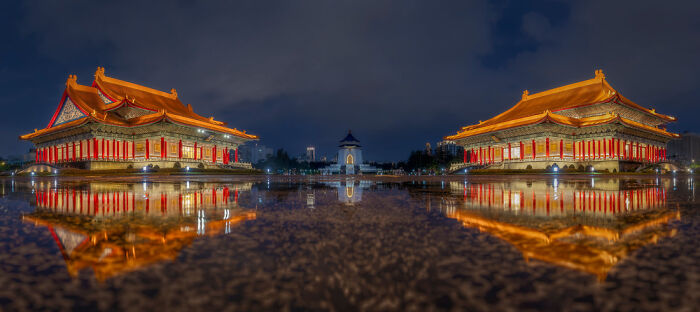 Panoramic masterpiece of traditional Asian architecture reflected in calm water under a dramatic night sky.