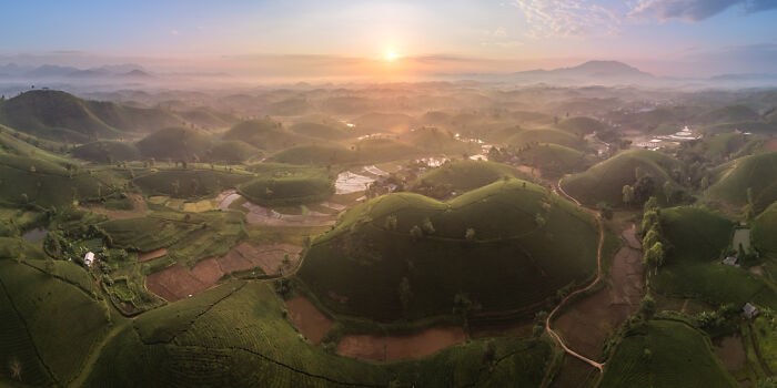 Panoramic landscape of rolling green hills and fields at sunrise, showcasing stunning panoramic masterpieces.