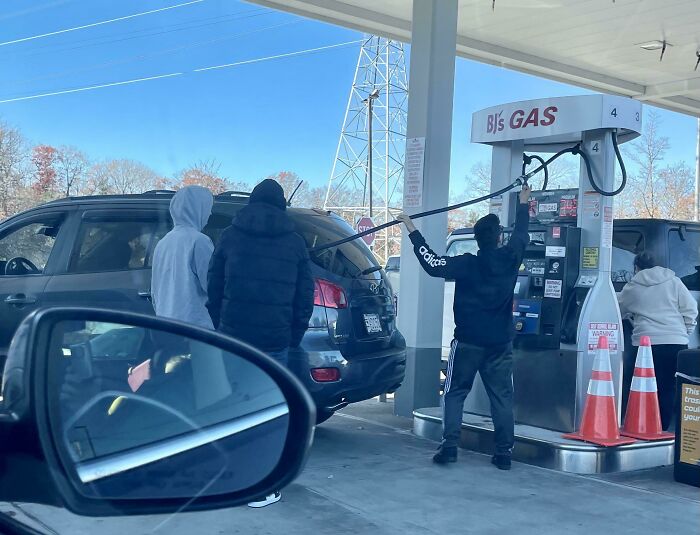 People with zero common sense holding a gas pump nozzle dangerously far from their vehicle at a gas station.