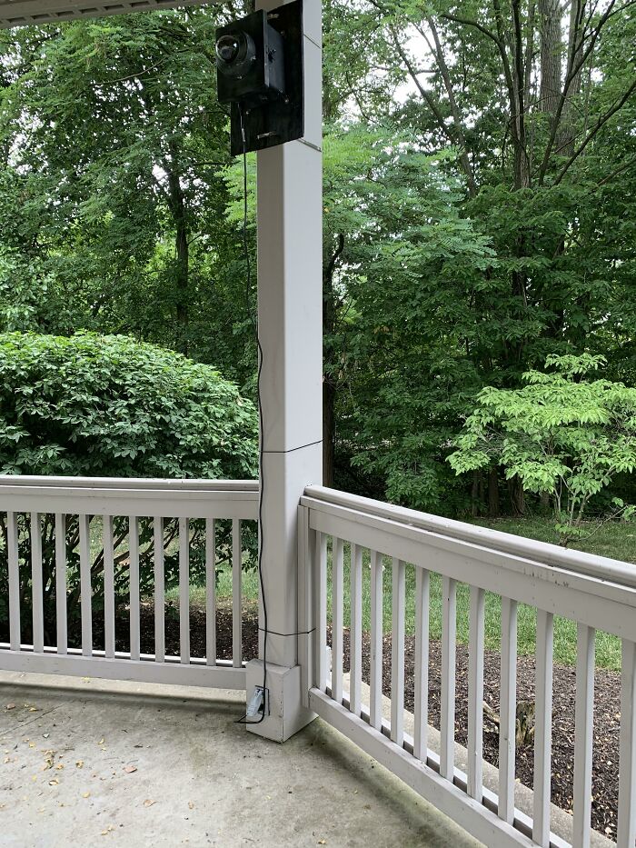 Outdoor porch with a speaker precariously mounted on a pillar, showing zero common sense in placement and wiring.