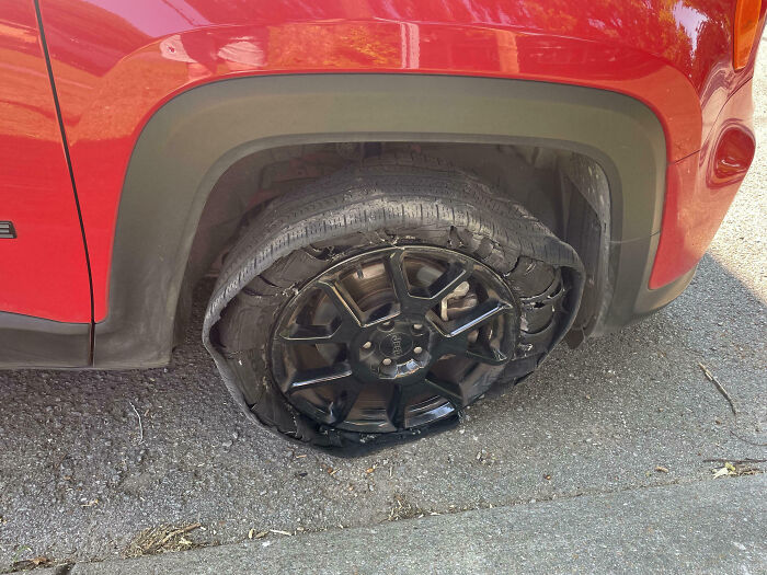 Flat tire on a red Jeep parked on the street, illustrating a total mess that reminds you it can always get worse.