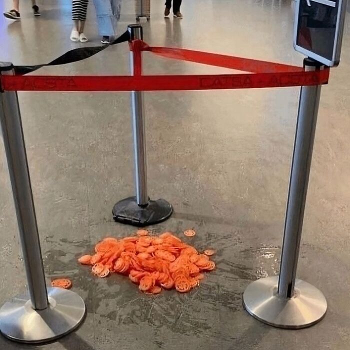 Pile of orange, slimy items cordoned off by a red barrier in a public space, a scene that might need a priest or exorcist.