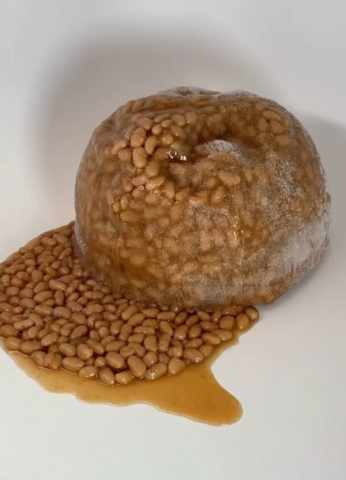 Frozen baked beans partially melted and leaking sauce on a white surface, a bizarre image that might need an exorcist.