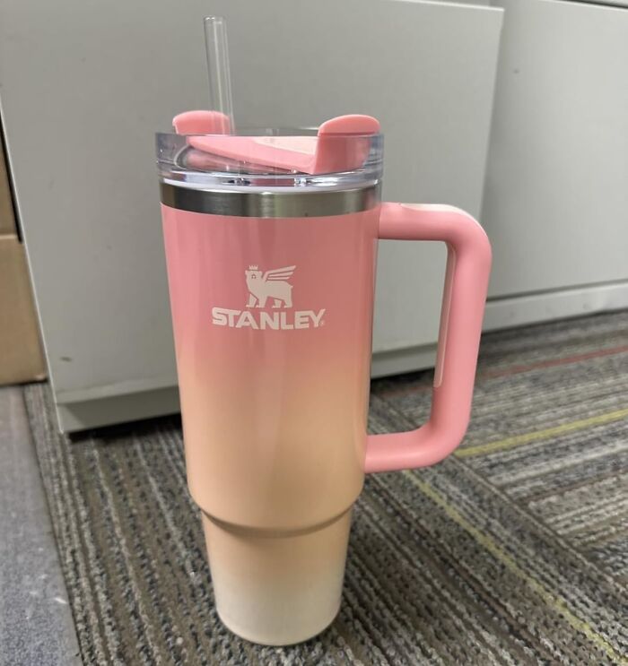 Pink gradient Stanley tumbler with handle and straw on carpeted floor, one of the viral products during Amazon deal days.