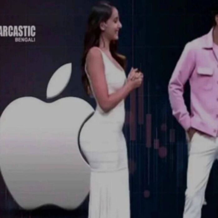 Woman in a white dress standing next to a giant Apple logo, an unusual image that might need a priest or an exorcist.