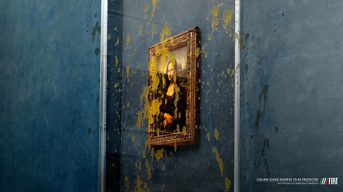 Mona Lisa painting covered in yellow paint splatters behind glass in creative ad campaign featuring iconic artwork.