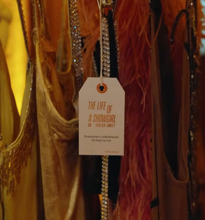 Clothing rack with a tag reading The Life of a Showgirl related to Taylor Swift and leaked lyrics backlash. Clothing rack with a tag reading The Life of a Showgirl related to Taylor Swift and leaked lyrics backlash.
