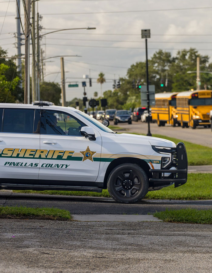 Pit Bull incident investigated by Pinellas County Sheriff's vehicle parked near a busy road with school buses in the background
