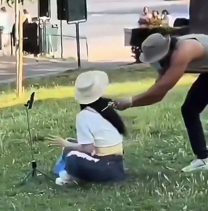 Influencer performing fake syringe prank on a woman in a park, capturing the staged attack on camera.
