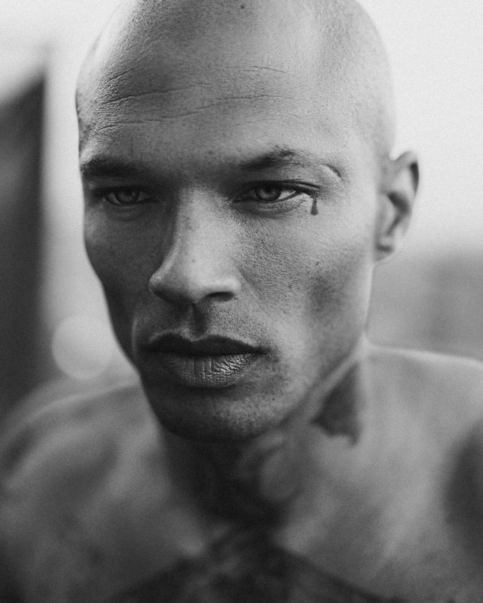 Close-up black and white portrait of the world's hottest felon at 41, showing intense expression and facial tattoo.