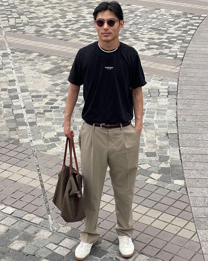 Man with no thumbs wearing sunglasses and black shirt standing on tiled pavement holding a large bag, showcasing life hacks and humor. Man with no thumbs wearing sunglasses and black shirt standing on tiled pavement holding a large bag, showcasing life hacks and humor.