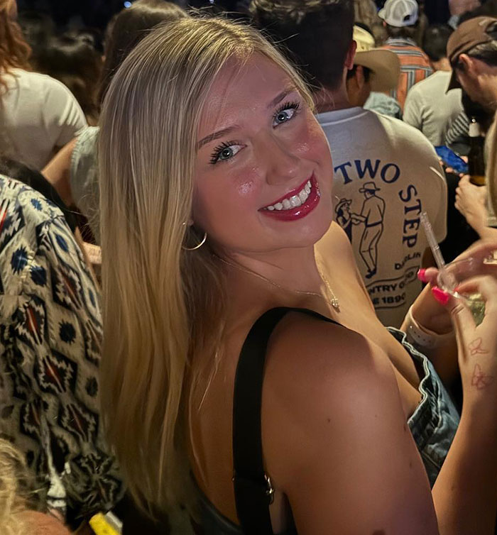 Young woman smiling at a crowded event, tied to student caught in Olive Garden hoax breaking silence. Young woman smiling at a crowded event, tied to student caught in Olive Garden hoax breaking silence.